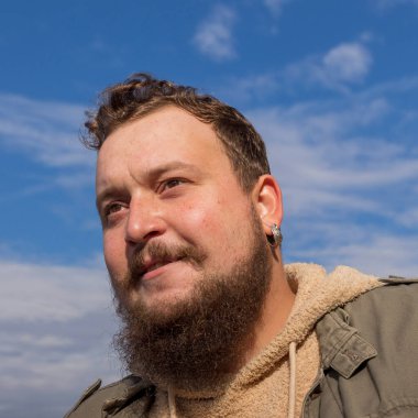 Bıyıklı, sakallı ve orta kulaklı genç bir adam.