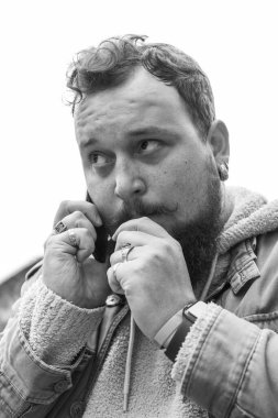 Sakallı genç bir adam sigara içiyor.