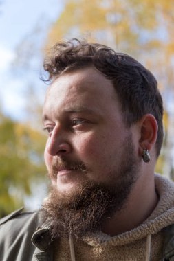 Bıyıklı, sakallı ve orta kulaklı genç bir adam.