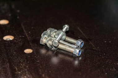 Siyah bir masada fındıklı metal cıvatalar.