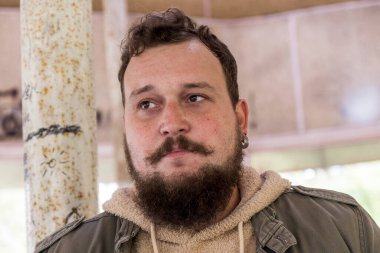 Sakallı ve bıyıklı bir gencin portresi.