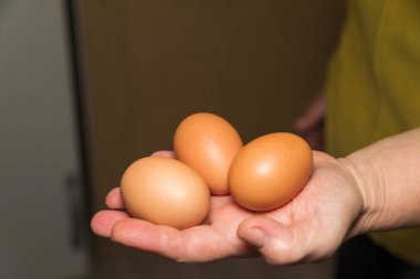 Mutfaktaki avuçlarında çiğ yumurta var. Çiftlikten ev yapımı tavuk yumurtası.