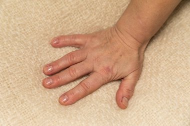 Kumaşın üzerinde bir kadın eli. Kadın parmakları ve avuç içi