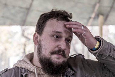 Sakallı ve bıyıklı genç bir adamın kafası karışıktır ve kendini güvensiz hisseder. Adam bir şeyler düşünmüş.