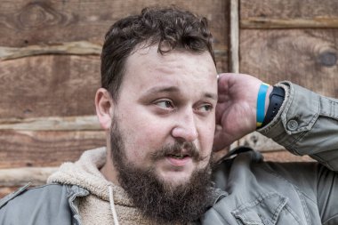 Sakallı ve bıyıklı genç bir adamın kafası karışıktır ve kendini güvensiz hisseder. Adam bir şeyler düşünmüş.