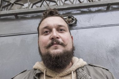 Sakallı ve bıyıklı bir gencin portresi.