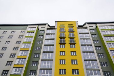 Büyük bir konut binasının cephesi. Renkli sarı ve yeşil duvarlar, pencereler ve balkonlar