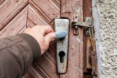 Çiftlikteki eski kapıyı bir adam elleriyle açıyor.