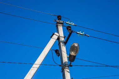 Elektrik kabloları ve gökyüzünün arka planında bir fener olan bir direk.