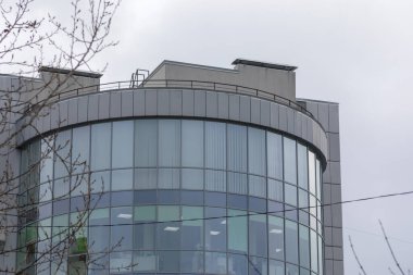 Gökyüzünün arka planında yuvarlak bir alışveriş merkezinin cam cephesi