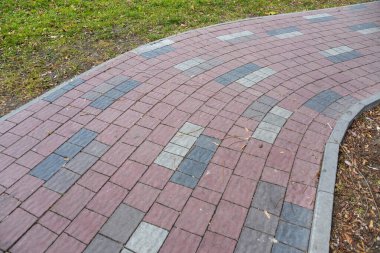 Parkta yuvarlak bir yol var. Arkaplan için kırmızı-gri dikdörtgen kaldırım