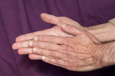 Yaşlı adam üşüdüğü için ellerini ovuşturuyor.