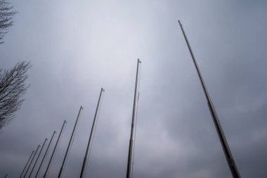 Parktaki rıhtım göletindeki bayraklar için metal bayrak direkleri