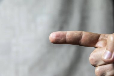 Adam parmaklarını gri arka planda gösteriyor. El hareketleri