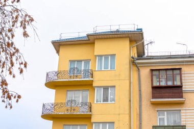 Pencereleri ve balkonları olan sarı bir apartmanın cephesi