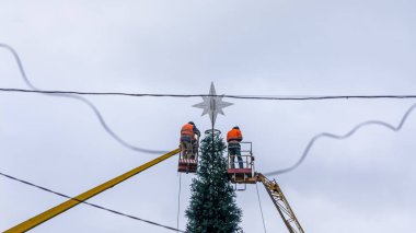 Elektrik işçileri Noel ağacını süslüyor