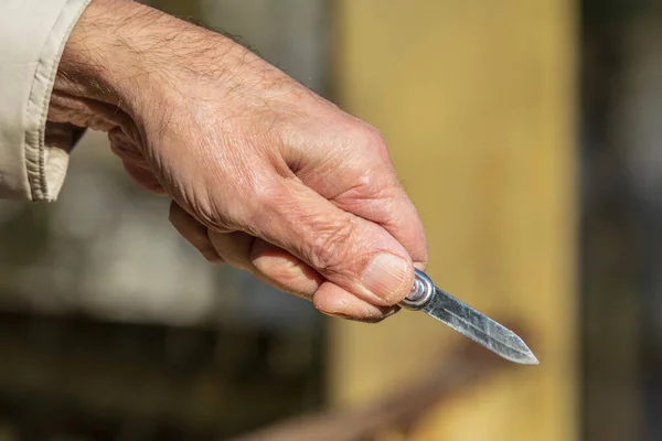 Metal shiny knife in the hand of an old man