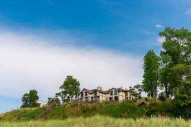 Otel yüksek bir deniz kıyısında yer almaktadır. Misafir evine giden merdivenler. Dinlenmek ve geceyi geçirmek için bir yer. Yeşilliklerin arasındaki tepede modern bir yapı. Deniz manzaralı bir ev..