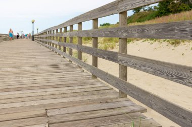 Deniz kıyısında parmaklıkları olan ahşap bir platform. Deniz boyunca sahil boyunca bir patika. Yol boyunca tahta korkuluklar. Öğleden sonra sahil boyunca platformda yürüyün..