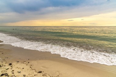 Kumsal kıyısı. Dalgalar çekildi. Kumlu bir sahilde dalgalar kırılıyor. Deniz kıyısı boyunca. Akşam havuzun üstüne düşüyor. Gün batımında deniz manzarası. Baltık Denizi kıyısında Tatil.
