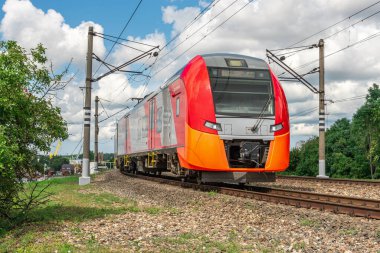 Elektrikli tren raylar boyunca hareket ediyor. Trenin demiryolu ile hareket etmesi. Şehir ortamında banliyö treni. Yeni lokomotif hareket halinde..