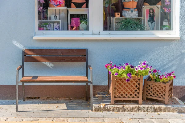 Dükkanın dışında çiçekli bir bank. Rahatlamak için açık bir yer. Çiçek saksıları bankın yanında. Mağazanın ön tasarımı. Pencerenin altında çiçekli bir bank var..
