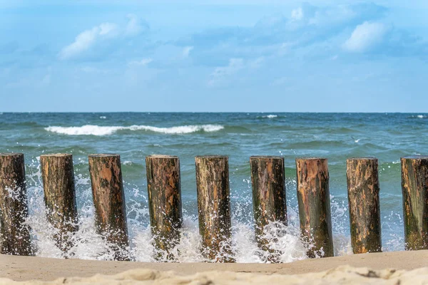 波罗的海海岸 海浪在沙滩上破裂了 石头躺在海滩上 人们在洗澡 海鸥在水面上飞翔 木制防波堤 — 图库照片