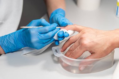 Müşterinin tırnaklarıyla uğraşan bir manikür ustası. Eller yakın çekim. Güzellik ve tırnak bakımı endüstrisi. Bir kadın güzellik salonunda profesyonel manikür yaptırıyor..