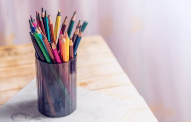 Masadaki bir fincanda renkli kalemler. Çocukların yaratıcılığı. Çizim için kalemler. Sanat eğitimi.