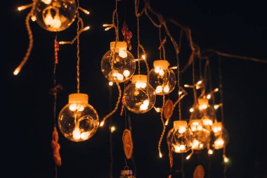 Karanlık bir arka planda yanan ampullerle dolu güzel, yaratıcı bir cam toplar çelengi. Noel ve yeni yıl arkaplanı. Sığ alan derinliği olan seçici bir odak noktası..