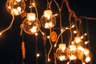 Karanlık bir arka planda yanan ampullerle dolu güzel, yaratıcı bir cam toplar çelengi. Noel ve yeni yıl arkaplanı. Sığ alan derinliği olan seçici bir odak noktası..