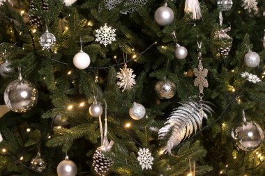 Noel ağacının beyaz ve gümüş Noel süslemeleri yakın planda. Yeni yılın arka planı. Sığ alan derinliği olan seçici odak.
