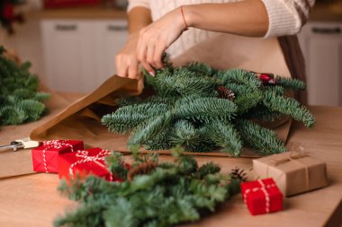 Evde köknar dallarından bir buket yapma süreci, kraft kağıdına sarma, kadının ellerine yakın çekim. Yeni yıl, Noel ve çevre dostu kavram. Seçici odaklanma..