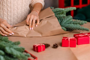 Evde köknar dallarından bir buket yapma süreci, kraft kağıdına sarma, kadının ellerine yakın çekim. Yeni yıl, Noel ve çevre dostu kavram. Seçici odaklanma..
