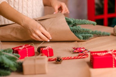Evde köknar dallarından bir buket yapma süreci, kraft kağıdına sarma, kadının ellerine yakın çekim. Yeni yıl, Noel ve çevre dostu kavram. Seçici odaklanma..