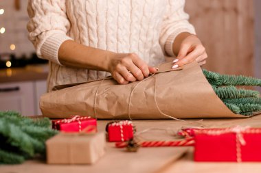 Evde köknar dallarından bir buket yapma süreci, kraft kağıdına sarma, kadının ellerine yakın çekim. Yeni yıl, Noel ve çevre dostu kavram. Seçici odaklanma..