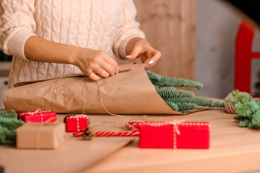Evde köknar dallarından bir buket yapma süreci, kraft kağıdına sarma, kadının ellerine yakın çekim. Yeni yıl, Noel ve çevre dostu kavram. Seçici odaklanma..