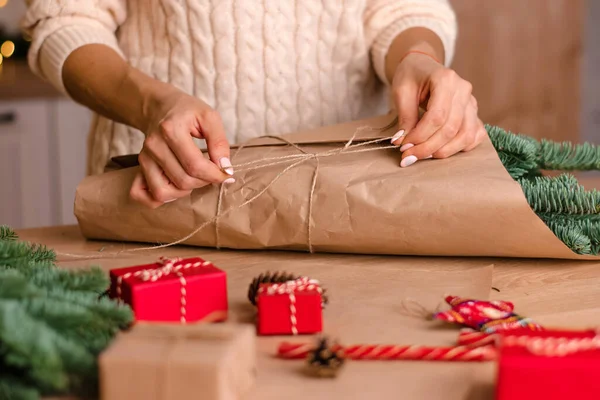 Evde köknar dallarından bir buket yapma süreci, kraft kağıdına sarma, kadının ellerine yakın çekim. Yeni yıl, Noel ve çevre dostu kavram. Seçici odaklanma..