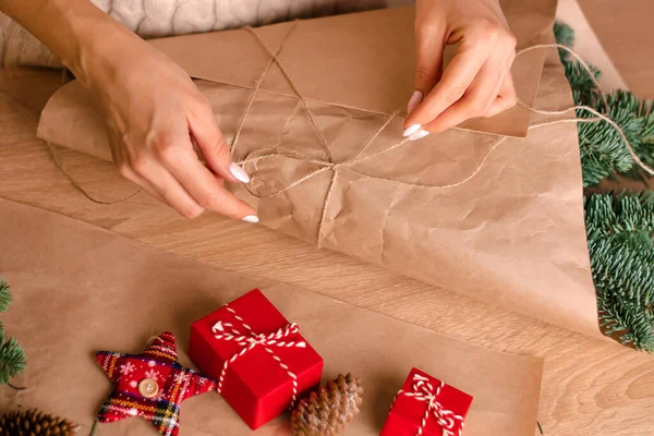 Evde köknar dallarından bir buket yapma süreci, kraft kağıdına sarma, kadının ellerine yakın çekim. Yeni yıl, Noel ve çevre dostu kavram. Seçici odaklanma..