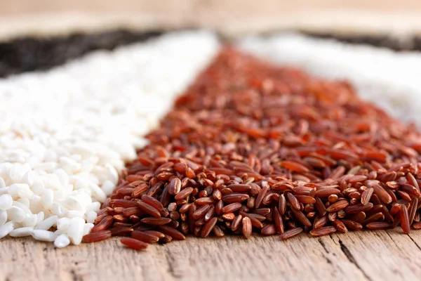 Different types of rice on the old wooden table — Stock Photo, Image