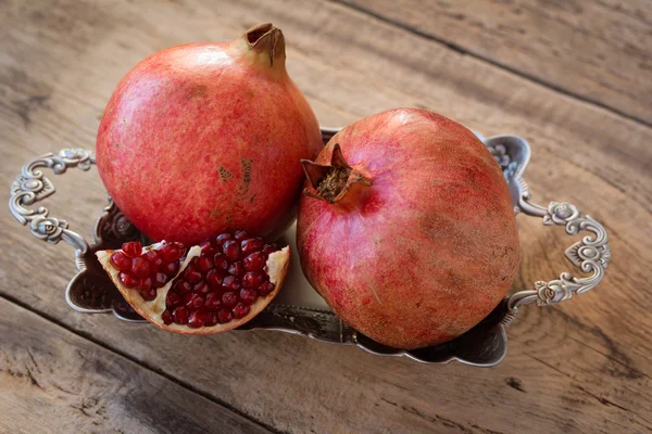 red pomegranates on a plate on old wooden table