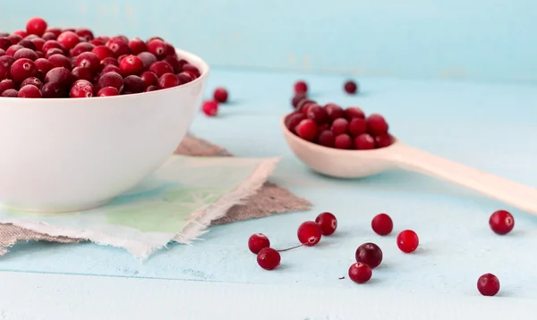 Frysta tranbär i skål på blå skrivbord — Stockfoto