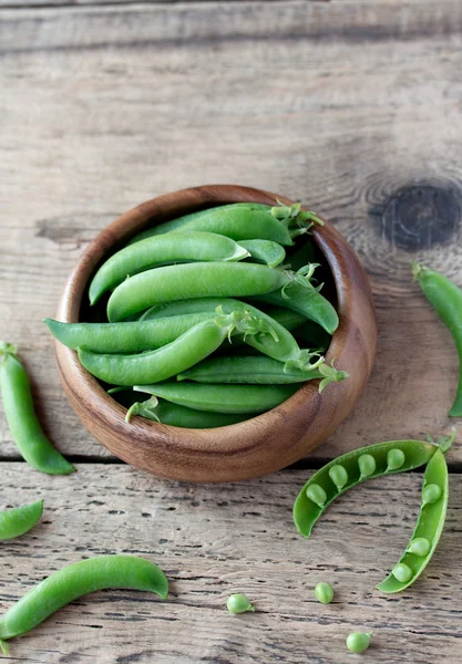 Wooden bowl full  of green peas pods. Top view. — Stock Photo, Image