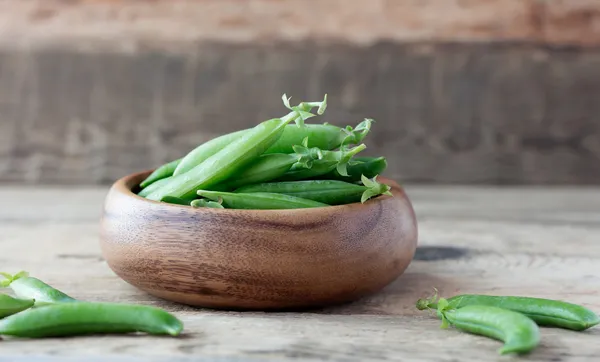 Wooden bowl full  of green peas pods — Stock Photo, Image