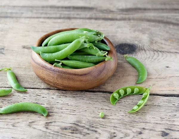 Wooden bowl full  of green peas pods — Stock Photo, Image