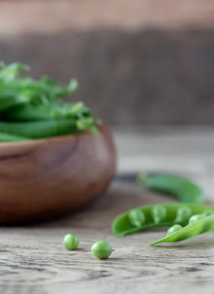 Wooden bowl full  of green peas pods — Stock Photo, Image