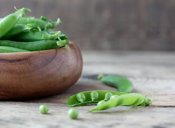 Wooden bowl full  of green peas pods — Stock Photo, Image