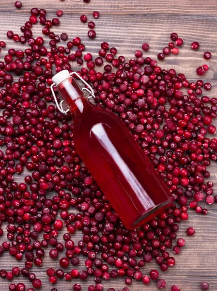 Ekologiska tranbär juice i flaska med bär på trä bakgrund — Stockfoto