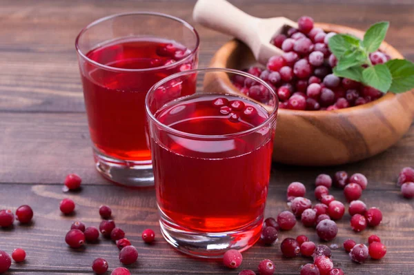 Suco de cranberry orgânico em copos com bagas em fundo de madeira — Fotografia de Stock