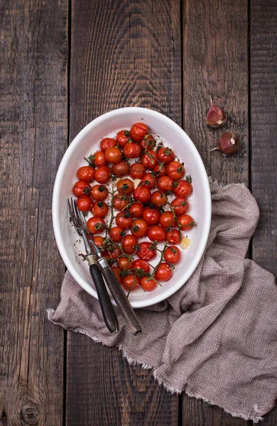 Tomates cherry asados con hierbas en bandeja para hornear. Imagen de archivo